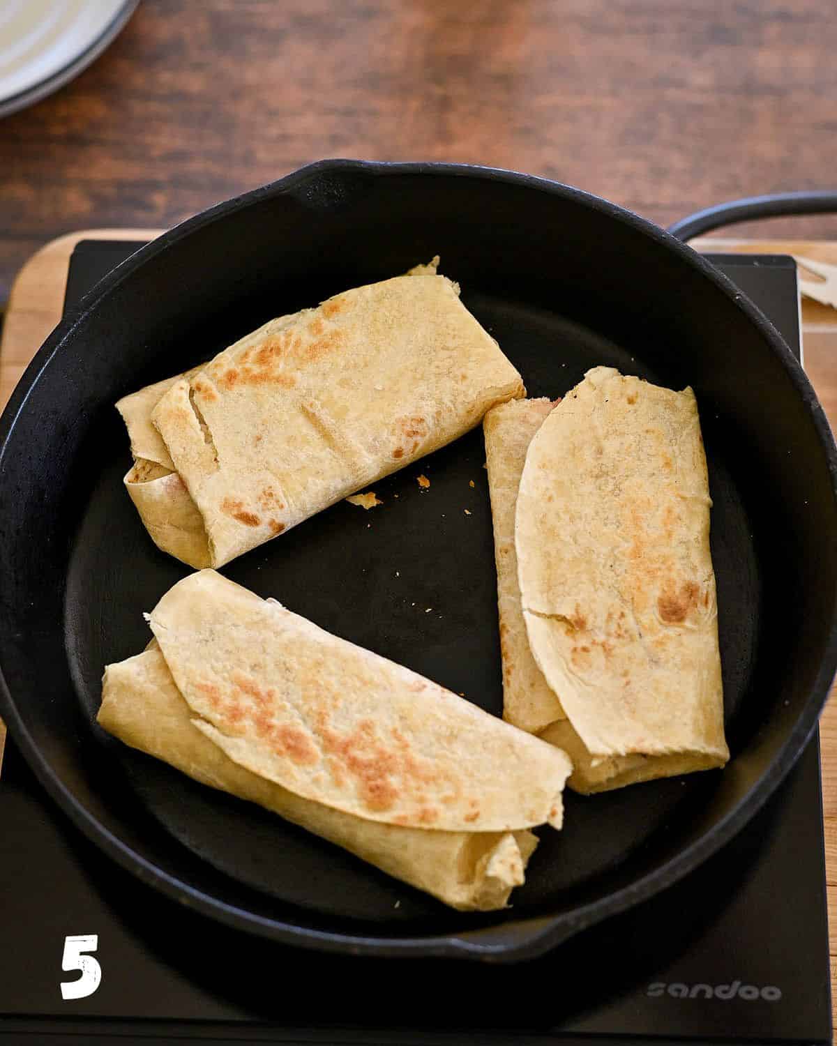 Stuffed tortillas turning golden brown after being cooked in a cast iron skillet. 
