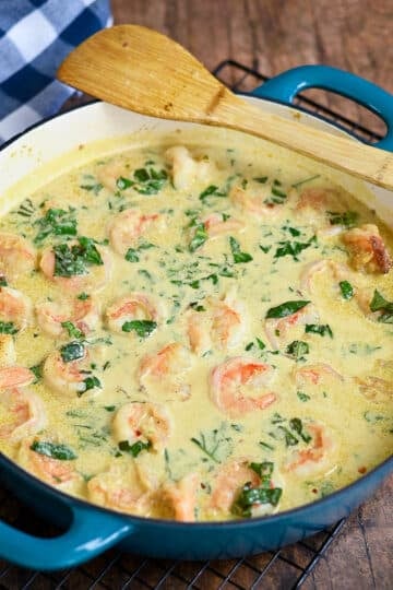A large skillet with shrimp, coconut milk, and basil ready to eat.