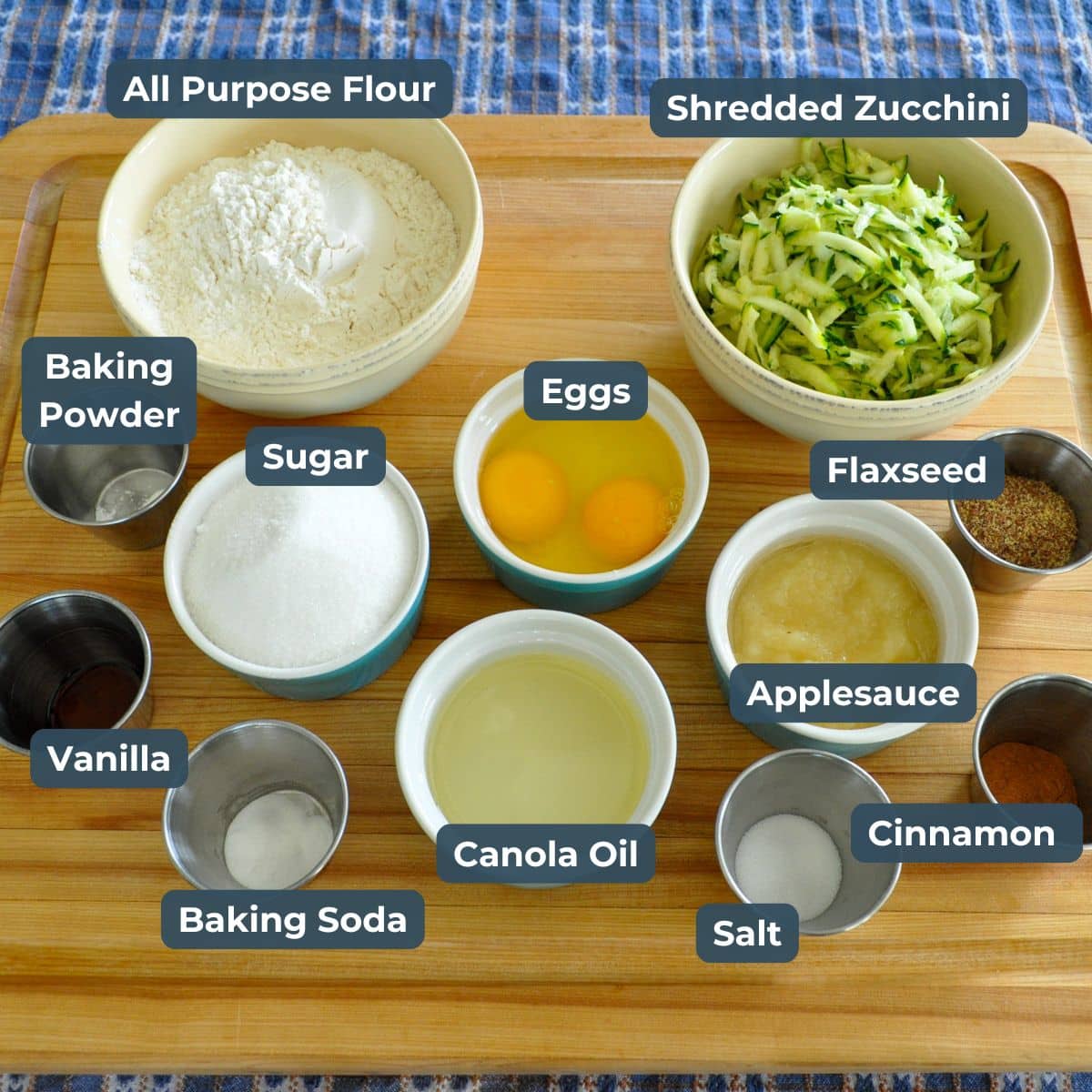 Ingredients for zucchini bread muffins: flour, shredded zucchini, eggs, applesauce, sugar, flaxseed, oil, spices, and more—perfect for creating delicious muffins with a twist of applesauce.