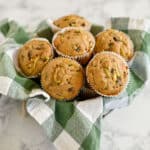 Basket of six Zucchini Bread Muffins with chocolate chips, made with applesauce and set on a green and white checkered cloth.
