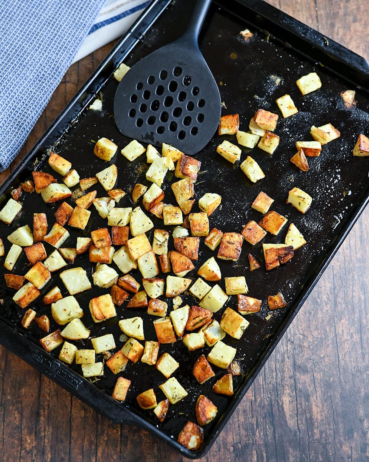 A baking sheet with golden brown roasted diced potatoes.