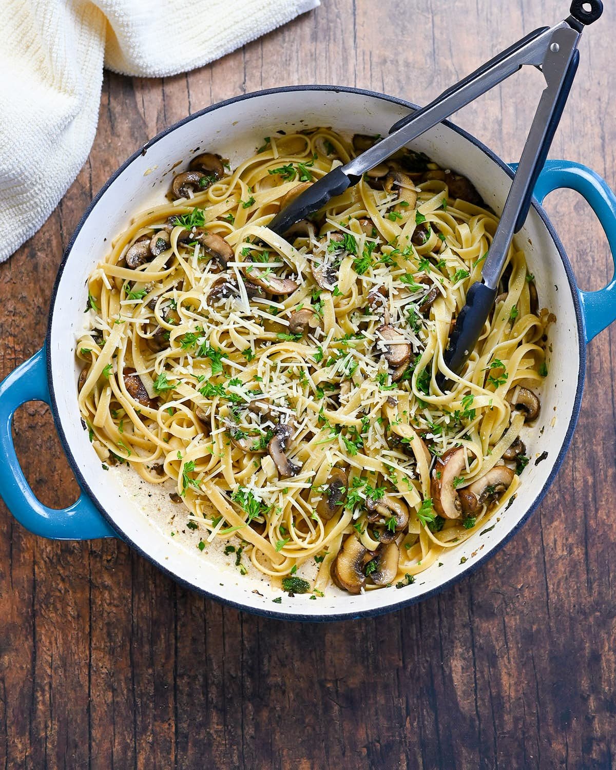 Pasta with mushrooms in a blue and white cast iron skillet. 