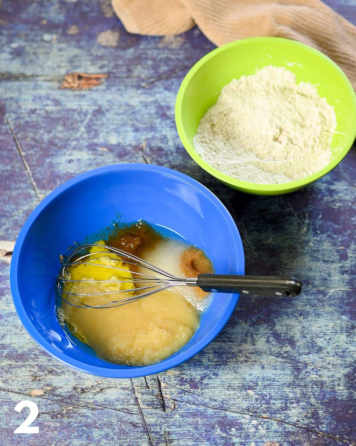 Applesauce and other wet ingredients in a blue bowl for cake batter.