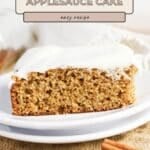 Slice of old-fashioned applesauce cake with white frosting on a plate, cinnamon sticks beside, and the Applesauce Cake Recipe title above.