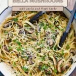 Pasta with Baby Bella Mushrooms, garlic, herbs, and grated cheese tossed in fettuccine, served in a white skillet with tongs.