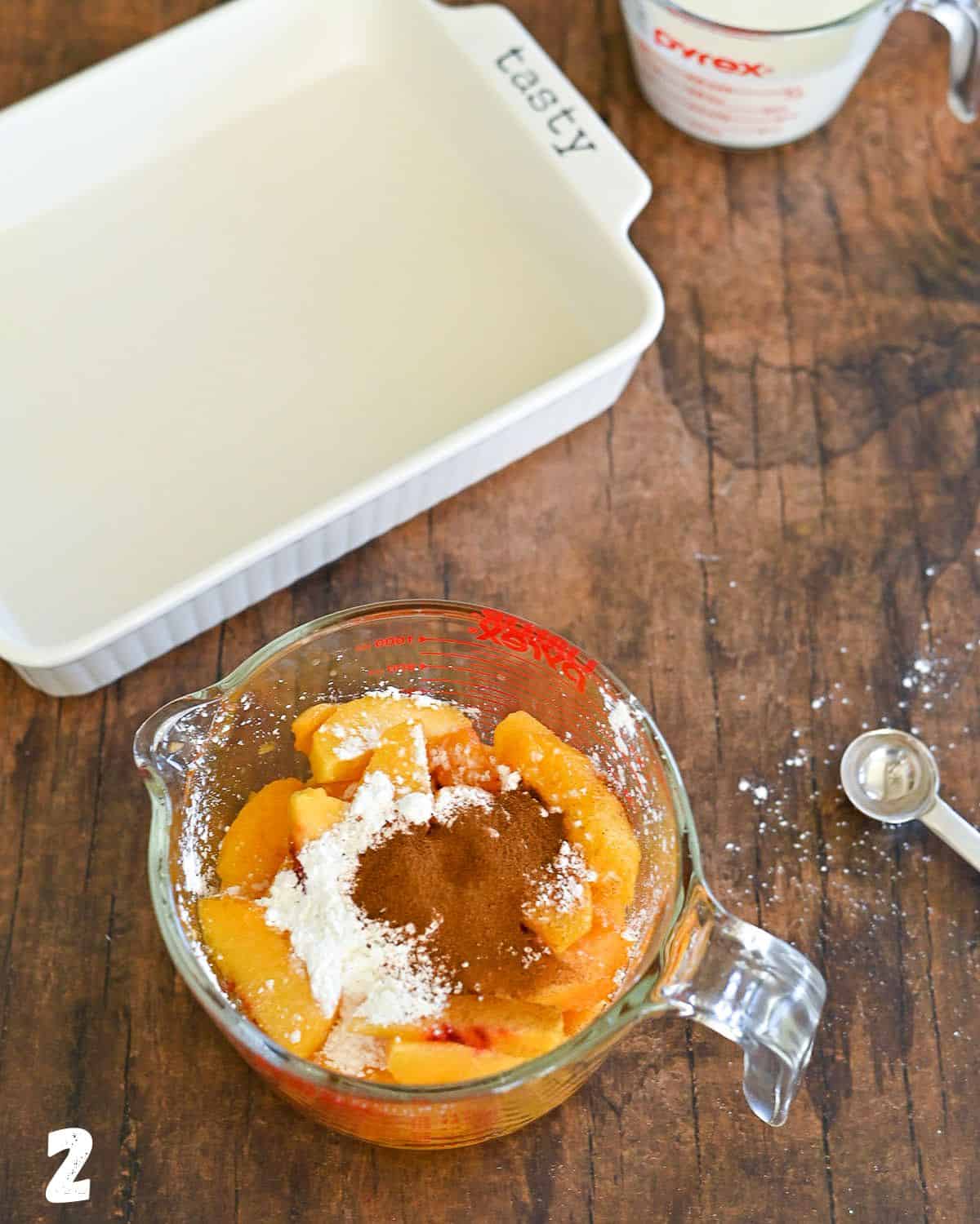 Peaches in a measuring cup topped with cinnamon and cornstarch.