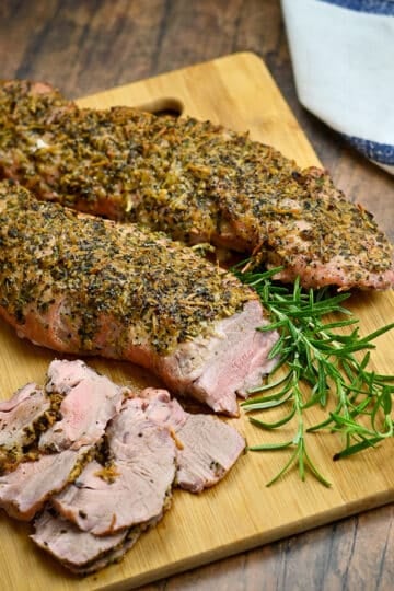 Sliced tenderloin on a wood cutting board ready to serve.