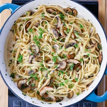 Pasta and herbs with mushrooms in a skillet.