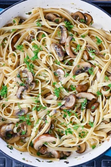 Pasta and herbs with mushrooms in a skillet.