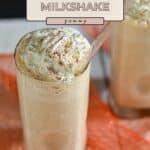 A creamy Pumpkin Milkshake topped with whipped cream and a sprinkle of cinnamon, served in a tall glass with a straw.