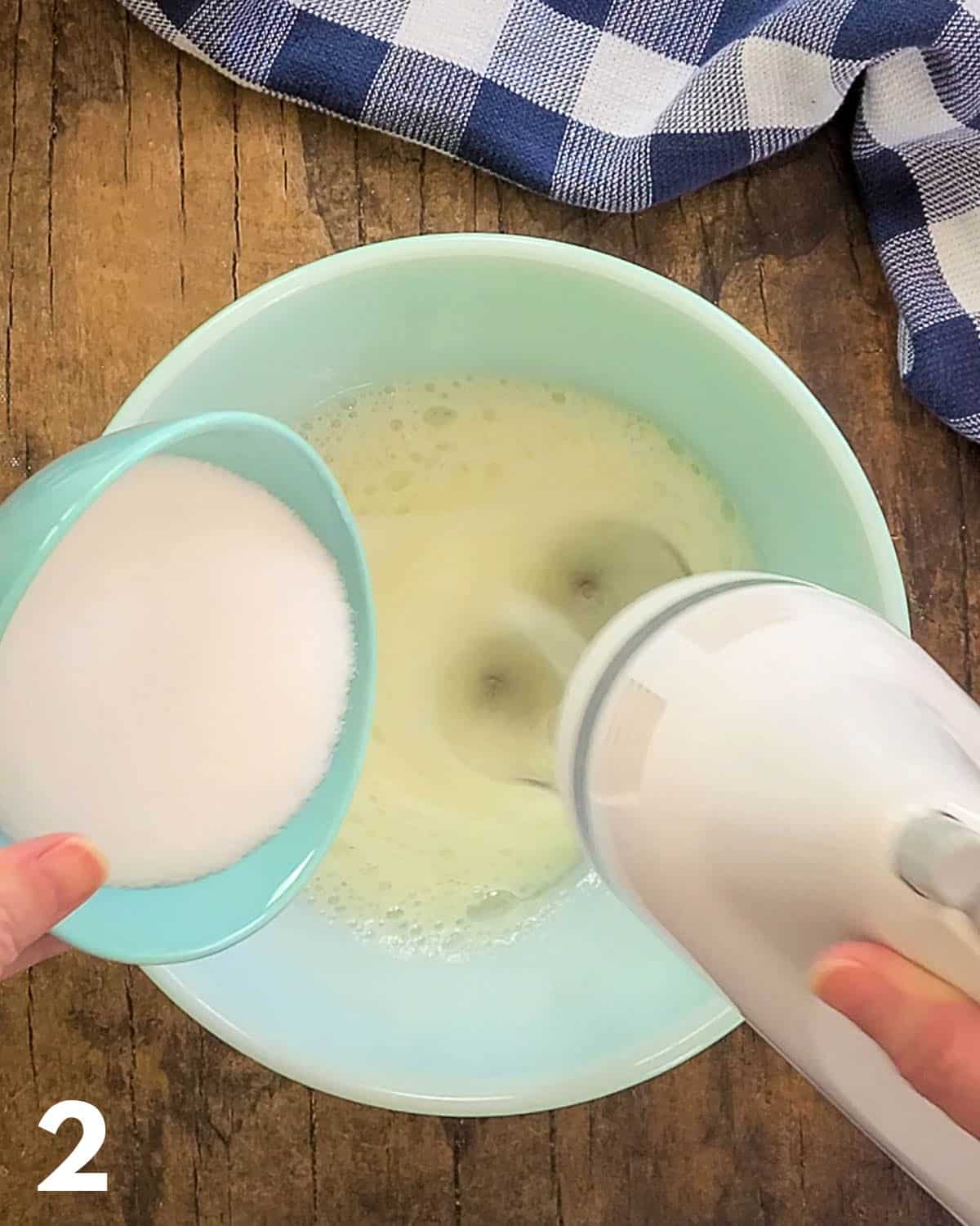 Sugar being added to egg whites while the mixer is going.