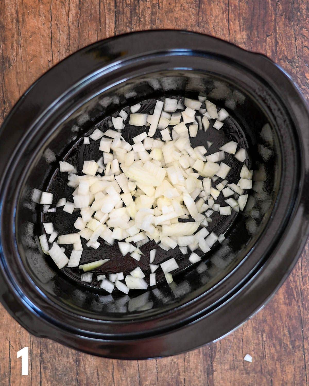 Chopped onion in a crock pot bowl. 