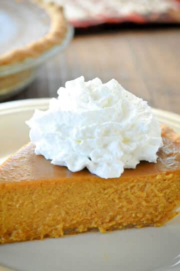 A slice of Butternut Squash Pie topped with whipped cream on a plate.