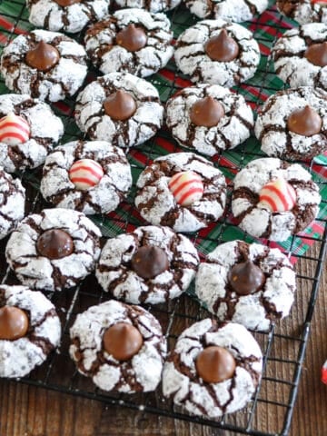 Chocolate crinkle cookies with a kiss on a cooling rack.