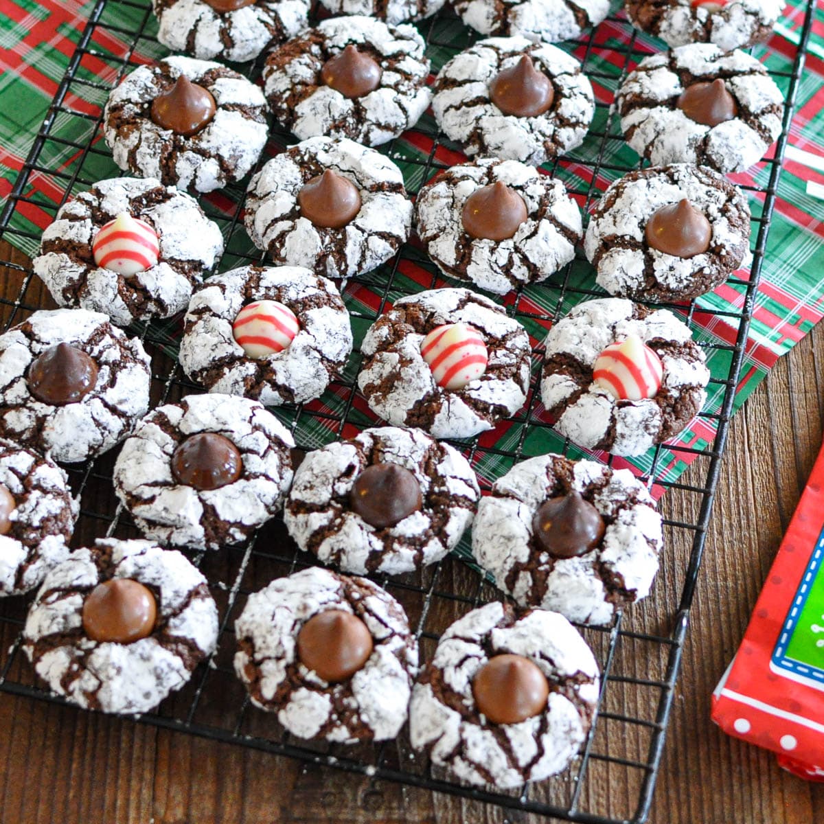 Chocolate crinkle cookies with a kiss on a cooling rack.