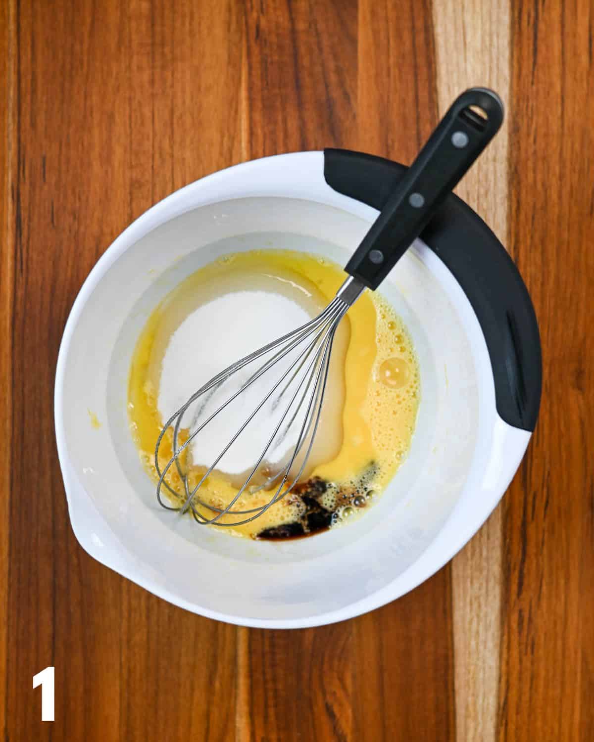 Eggs, sugar, and vanilla in a white mixing bowl.