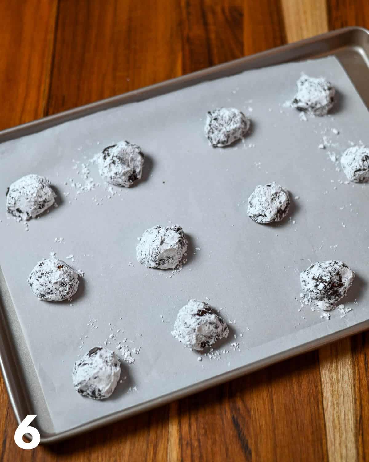 Powder sugar covered cookie dough on  a baking sheet ready to bake. 
