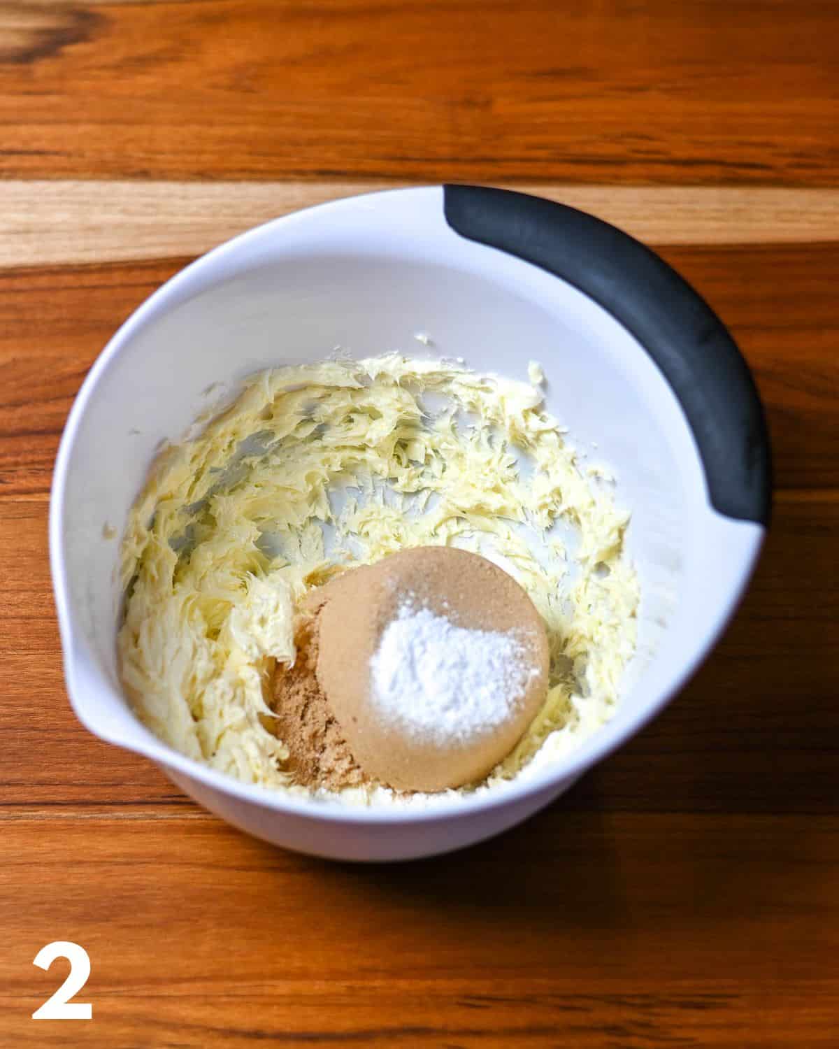 Brown sugar with baking powder over butter in a mixing bowl.