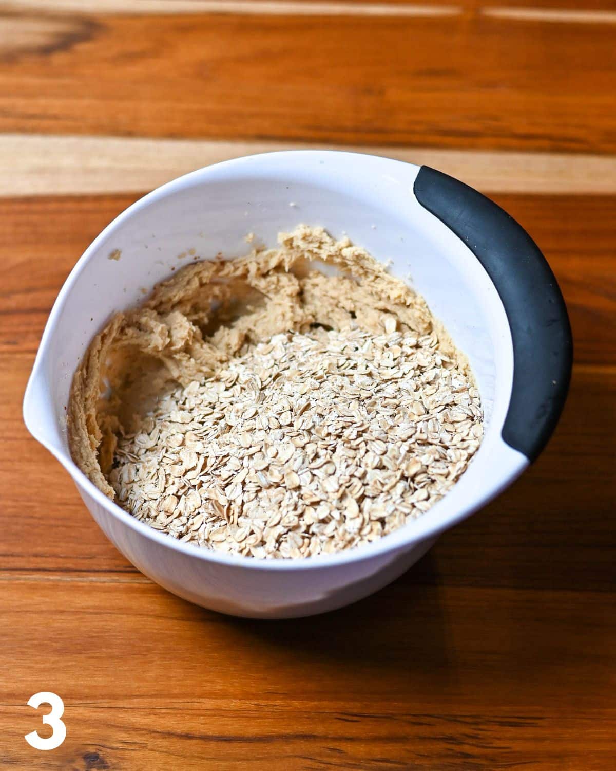 Oats added to mixed butter and brown sugar in a mixing bowl. 