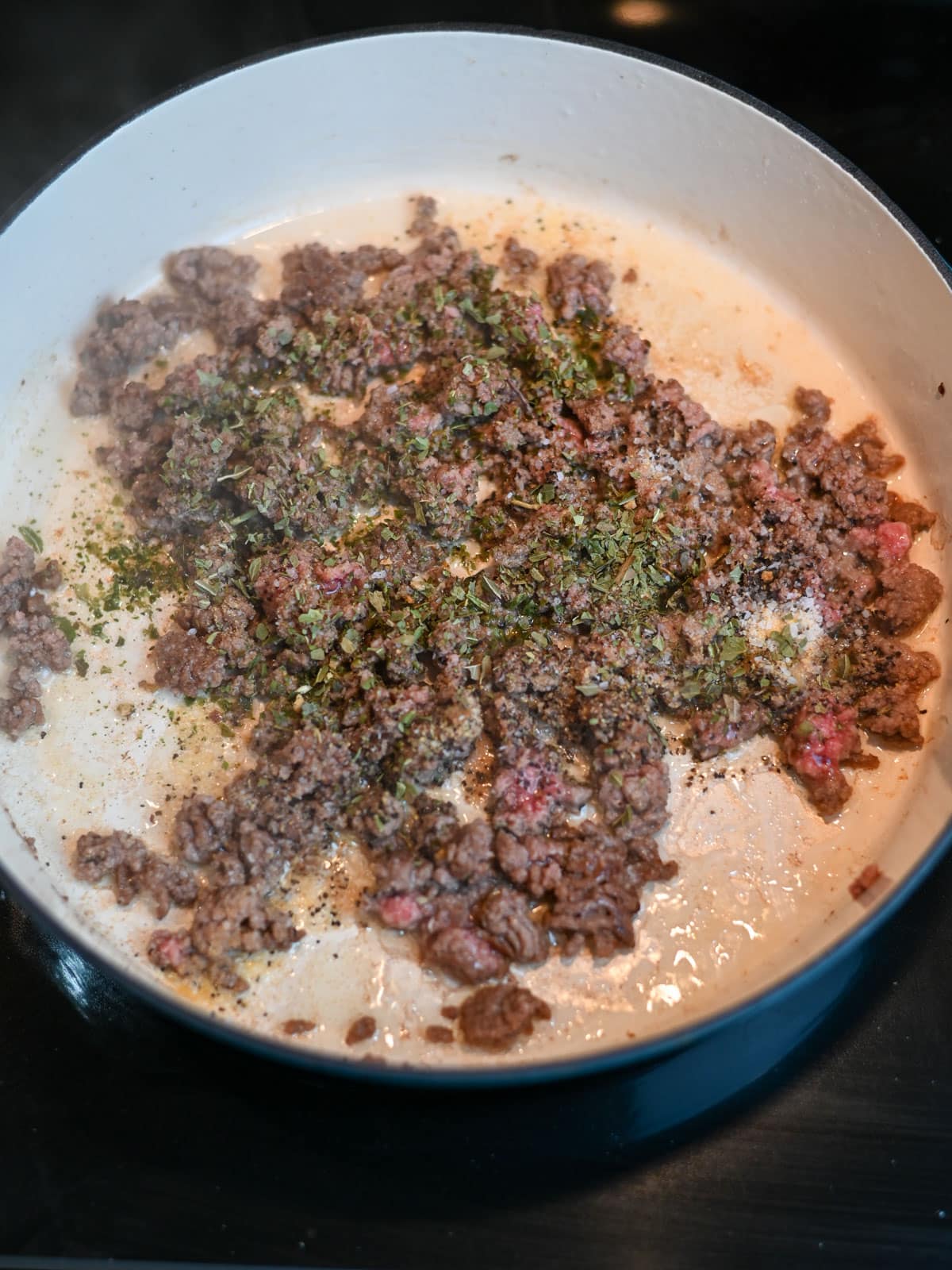 Seasoning added to cooking ground beef in a large skillet. 