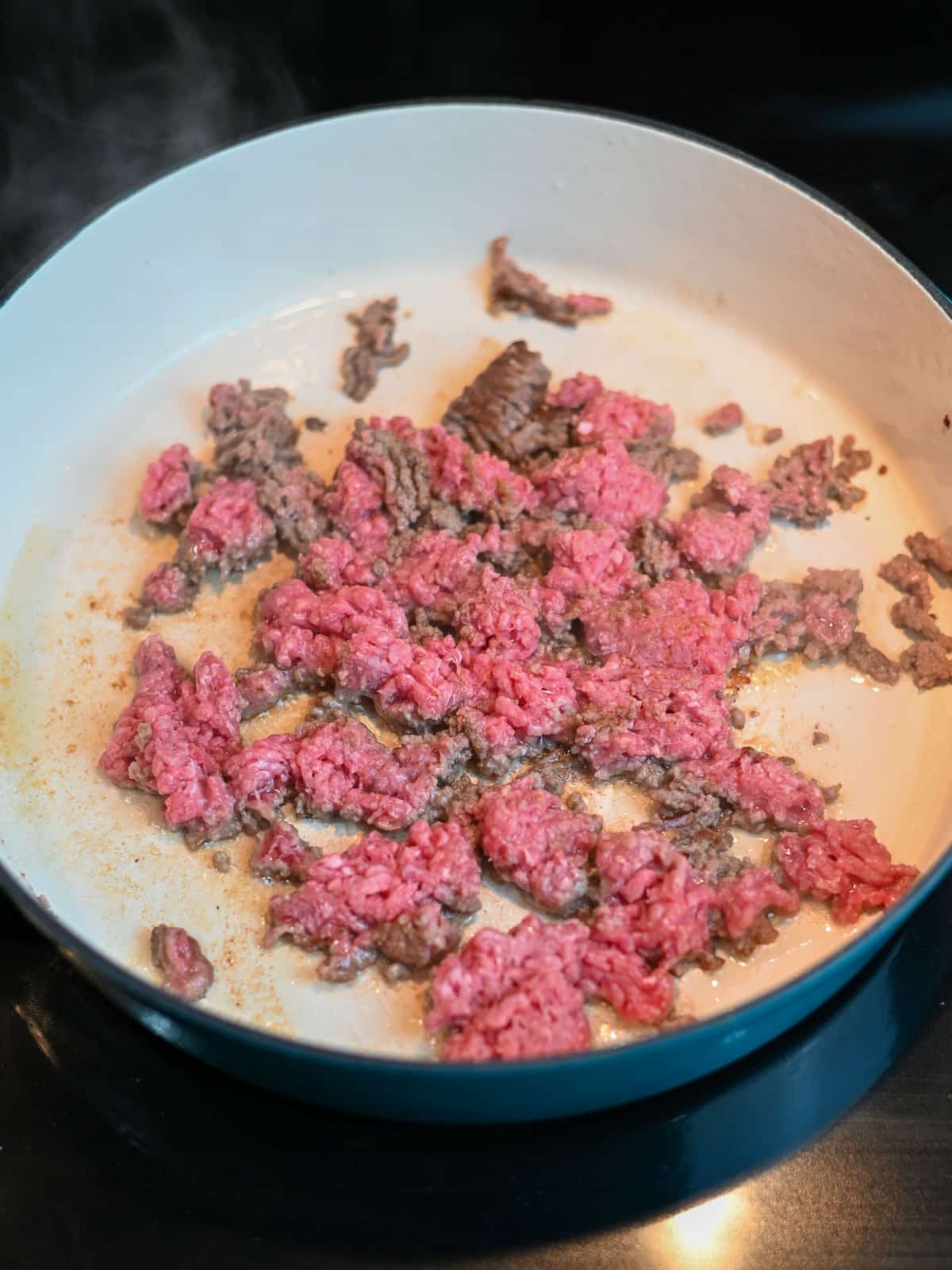 Brown beef starting to brown in a large skillet.