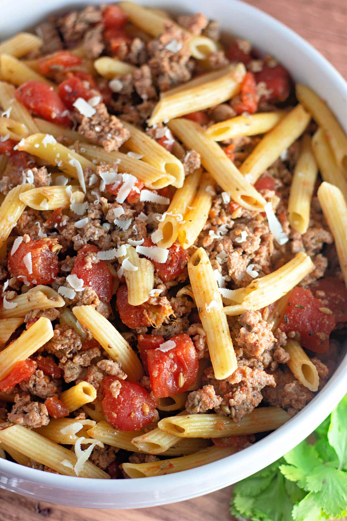 Ground turkey sausage with pasta and tomatoes in a white bowl.