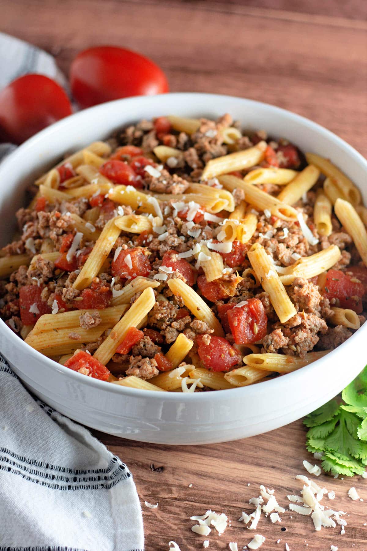 Ground turkey sausage with pasta and tomatoes in a white bowl.