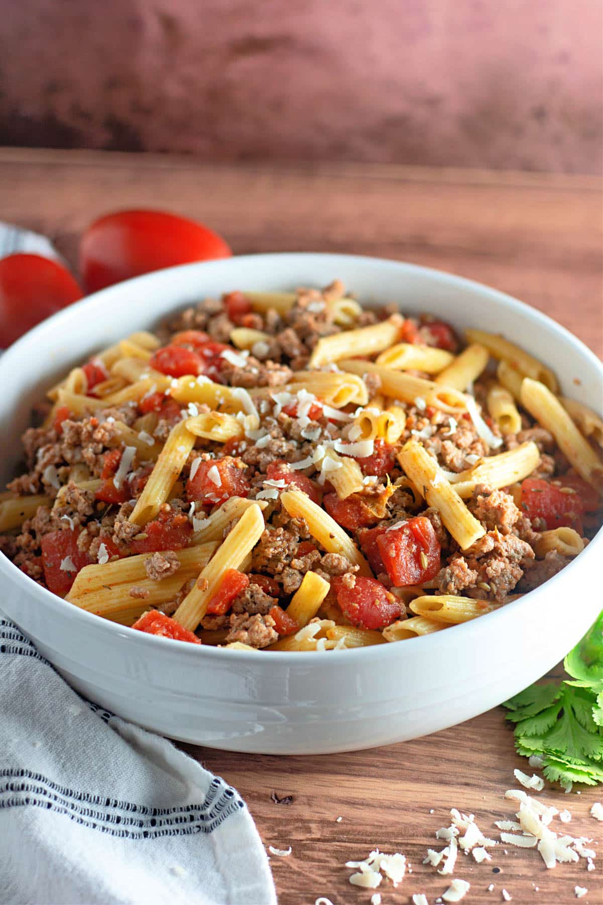 Ground turkey sausage with pasta and tomatoes in a white bowl.