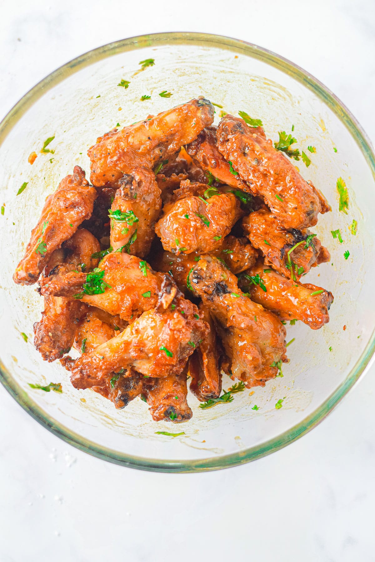 Bowl of crispy Air Fryer Honey Lime Chicken Wings coated in sauce and garnished with chopped herbs.