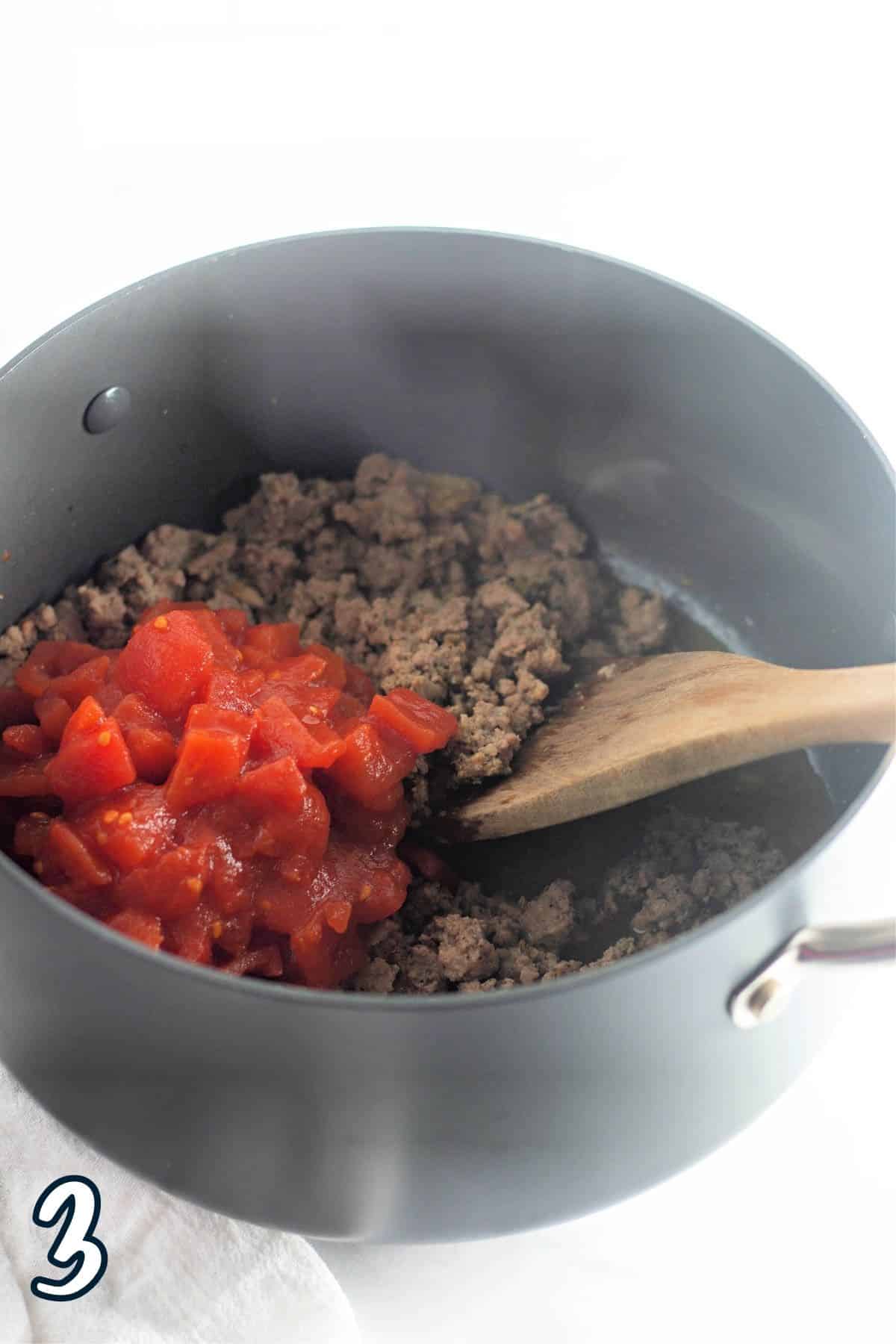 Ground turkey and diced tomatoes in a large pan.