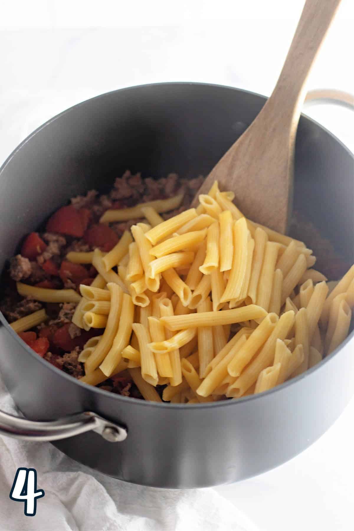 Cooked pasta added to a pan of spiced up ground turkey.