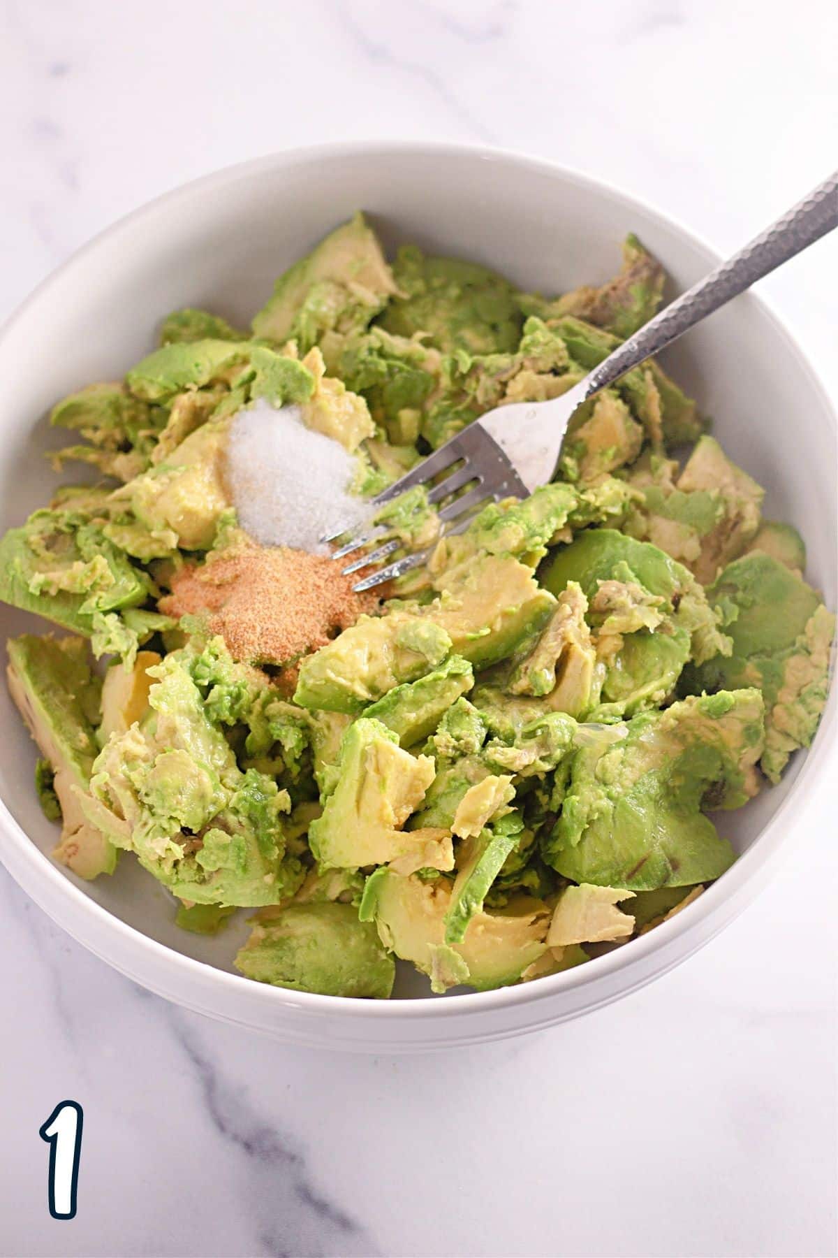Avocado chunks in a bowl with salt and garlic.