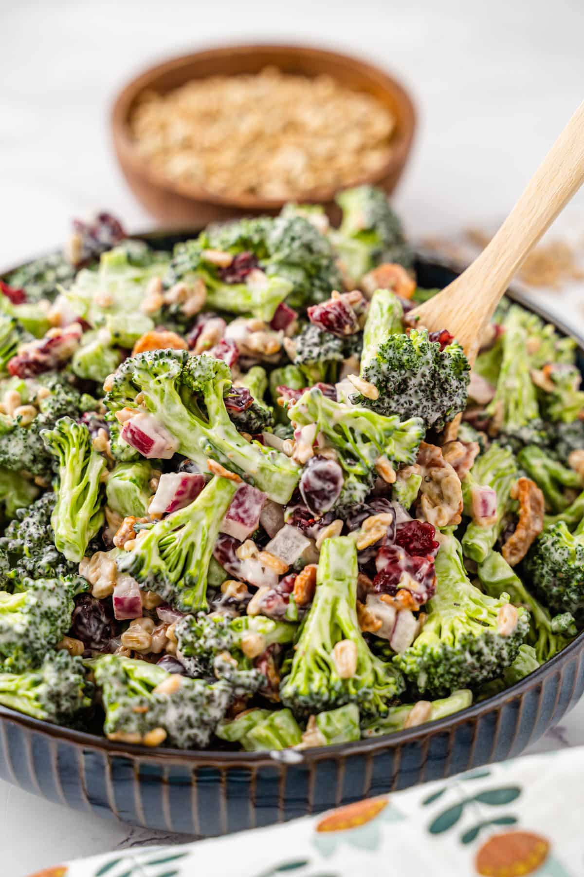 A black serving bowl filled with broccoli salad. 