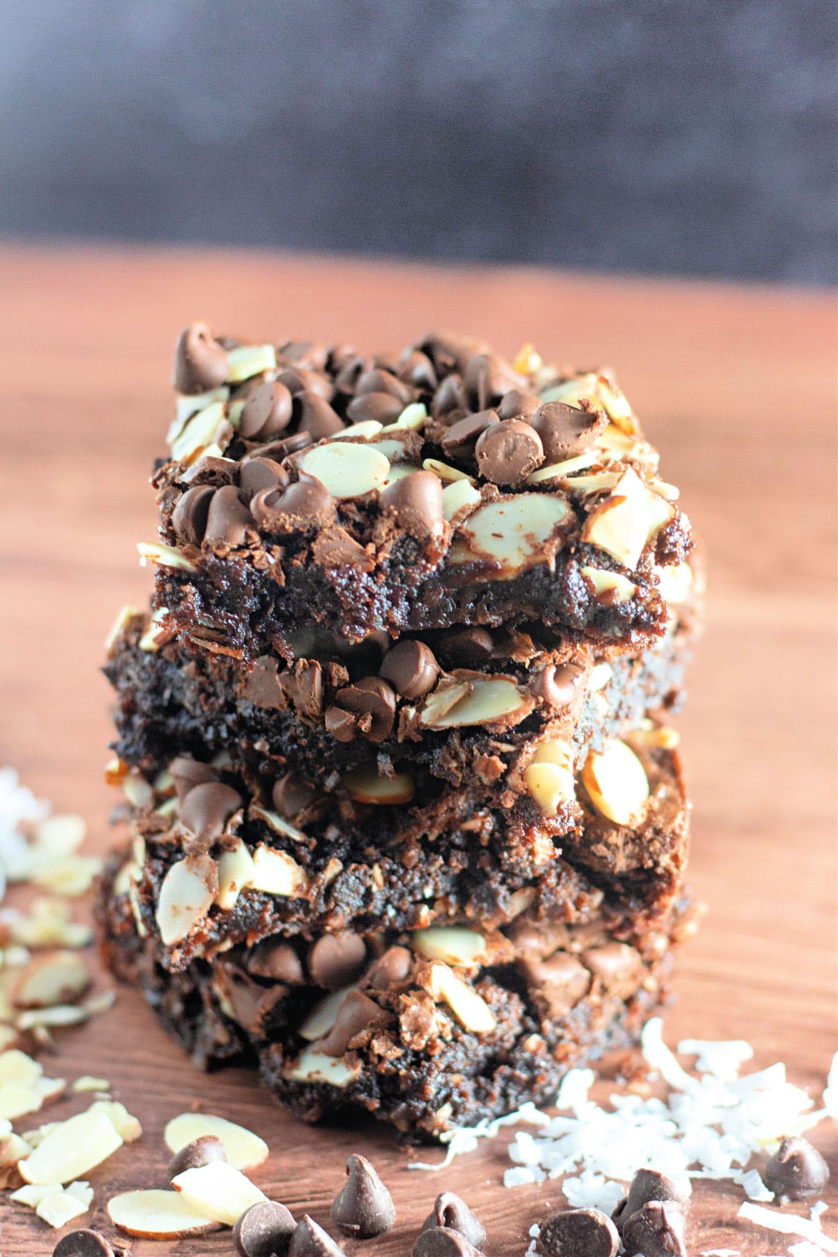 A stack of several coconut brownies on a wood backdrop.