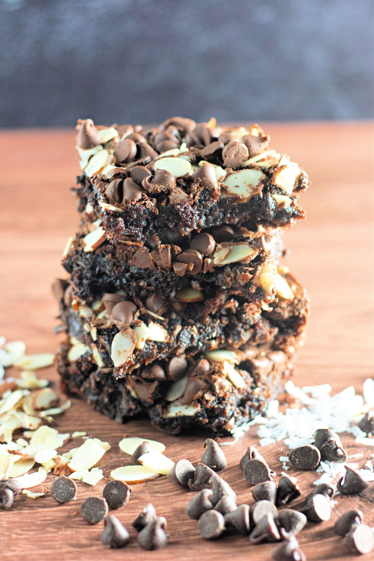 A stack of several coconut brownies on a wood backdrop. 