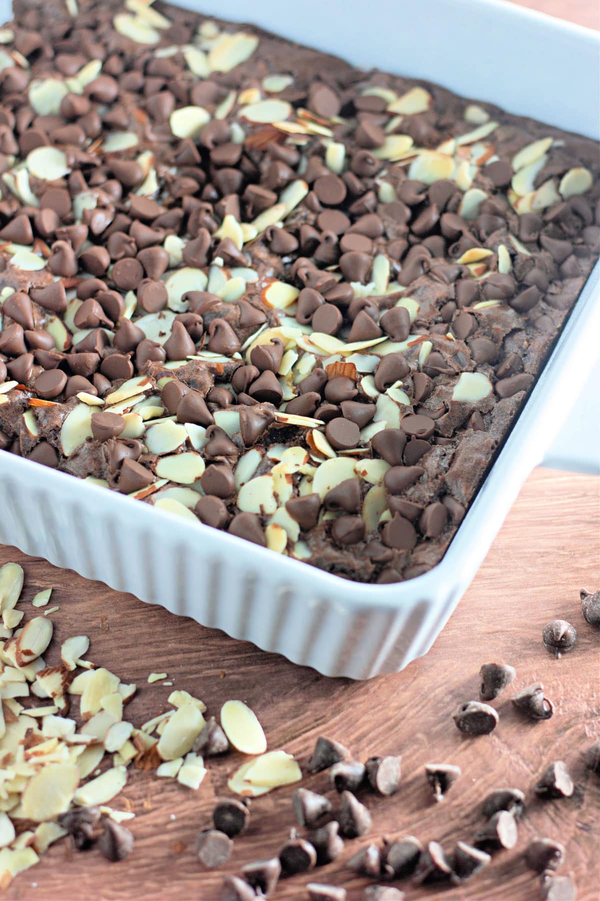 Just baked coconut brownies with almonds in a white baking dish.