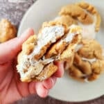 A fluffernutter cookie that has been broken in two being held.