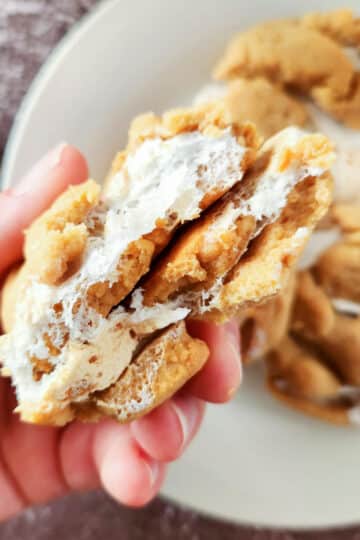 A fluffernutter cookie that has been broken in two being held.