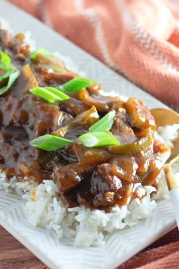 Homemade mongolian beef on a bed of rice on a white platter.
