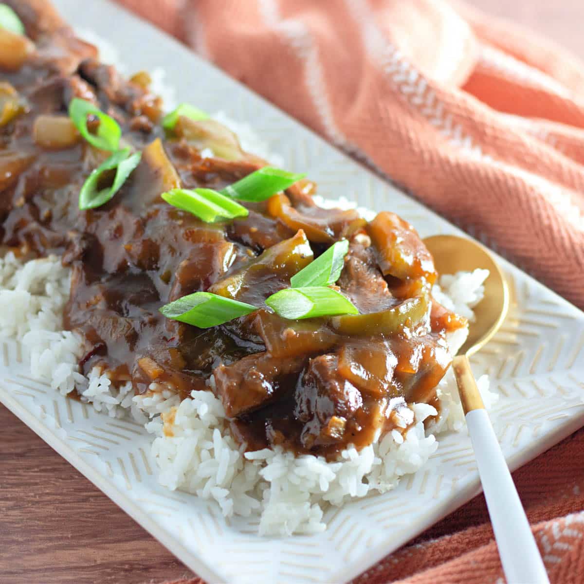 Homemade mongolian beef on a bed of rice on a white platter.