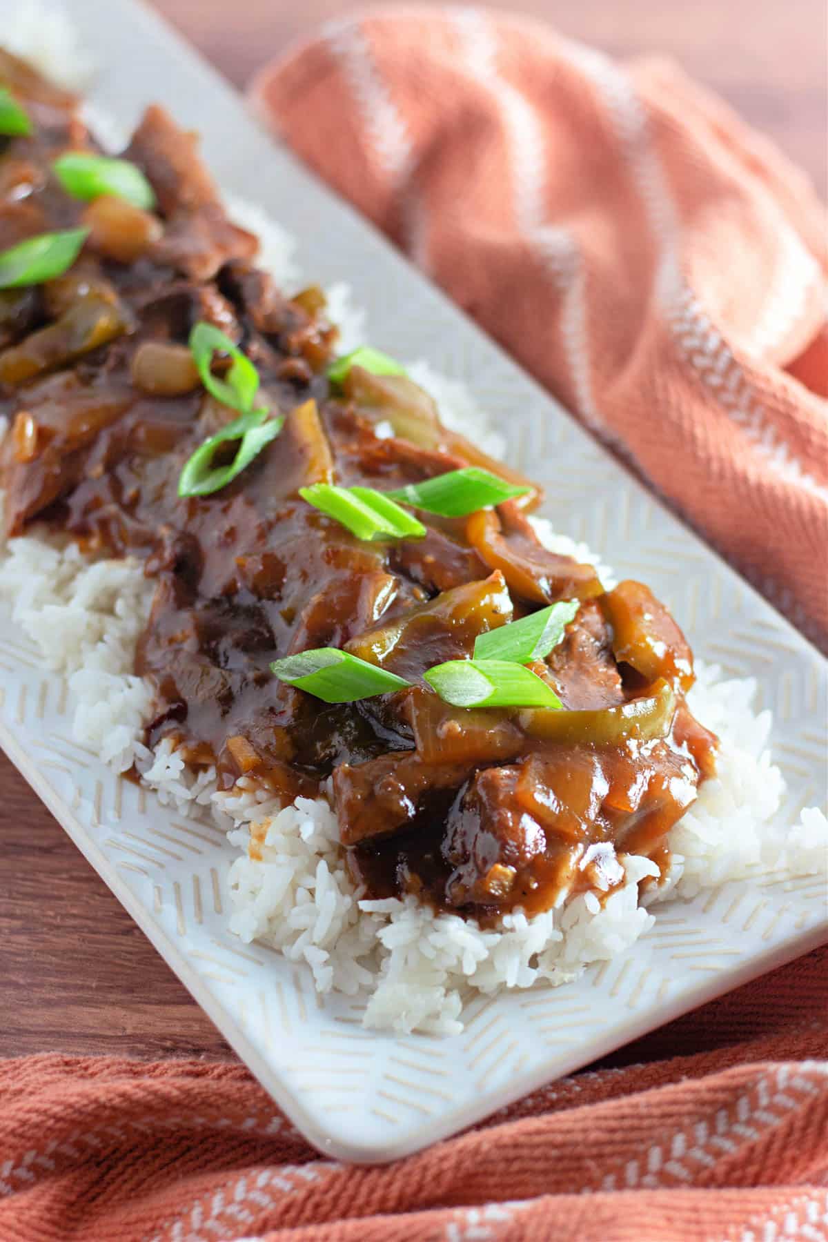 Homemade mongolian beef on a bed of rice on a white platter.