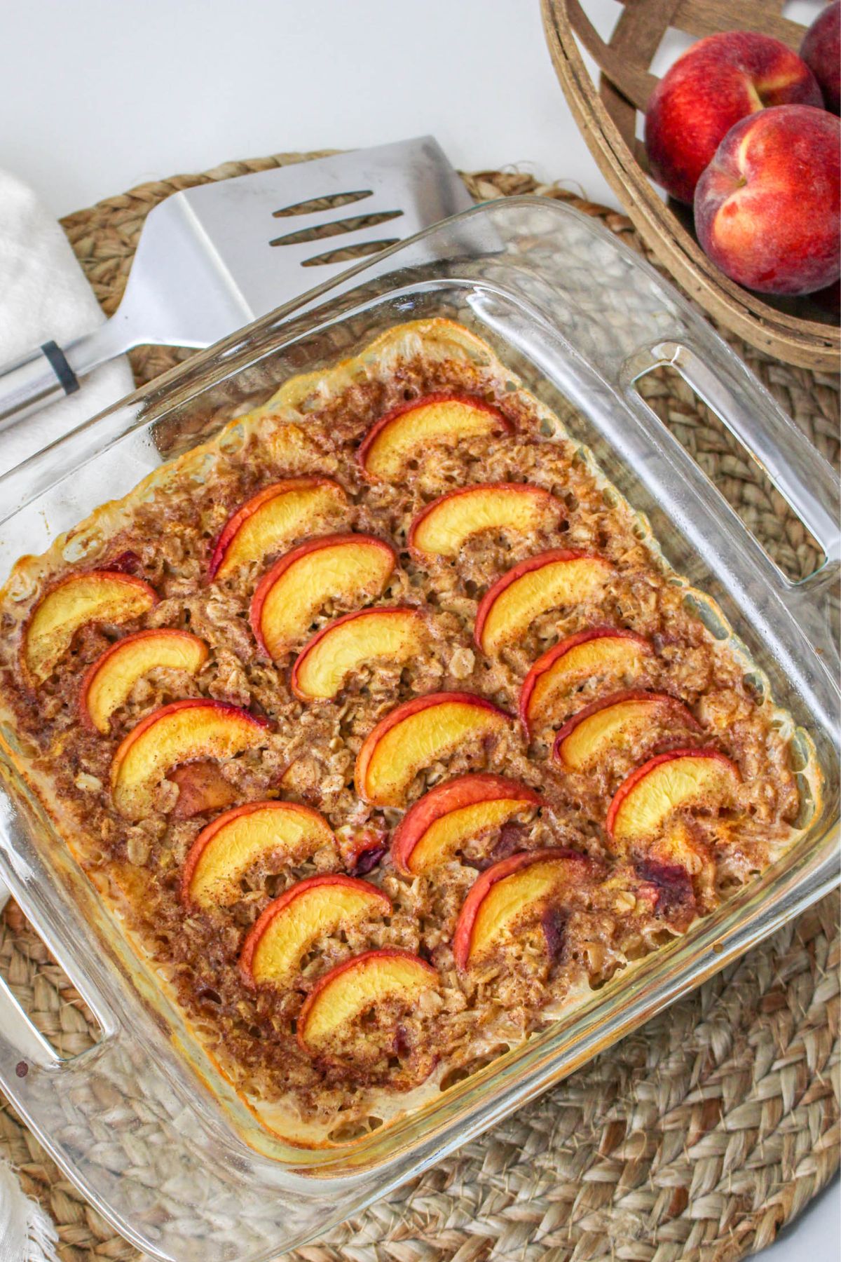 Baked oatmeal with peaches in a clear glass baking dish. 