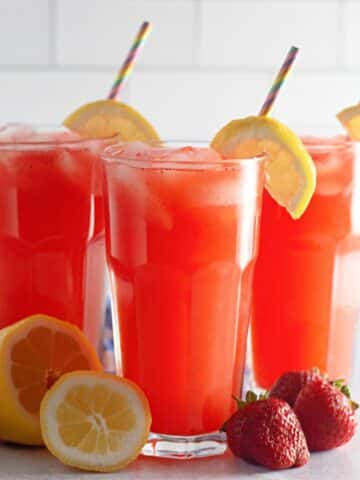 Three glasses of strawberry lemonade with straws.