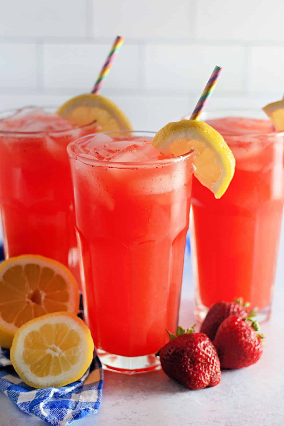 3 glasses of strawberry lemonade in clear glasses with straws.