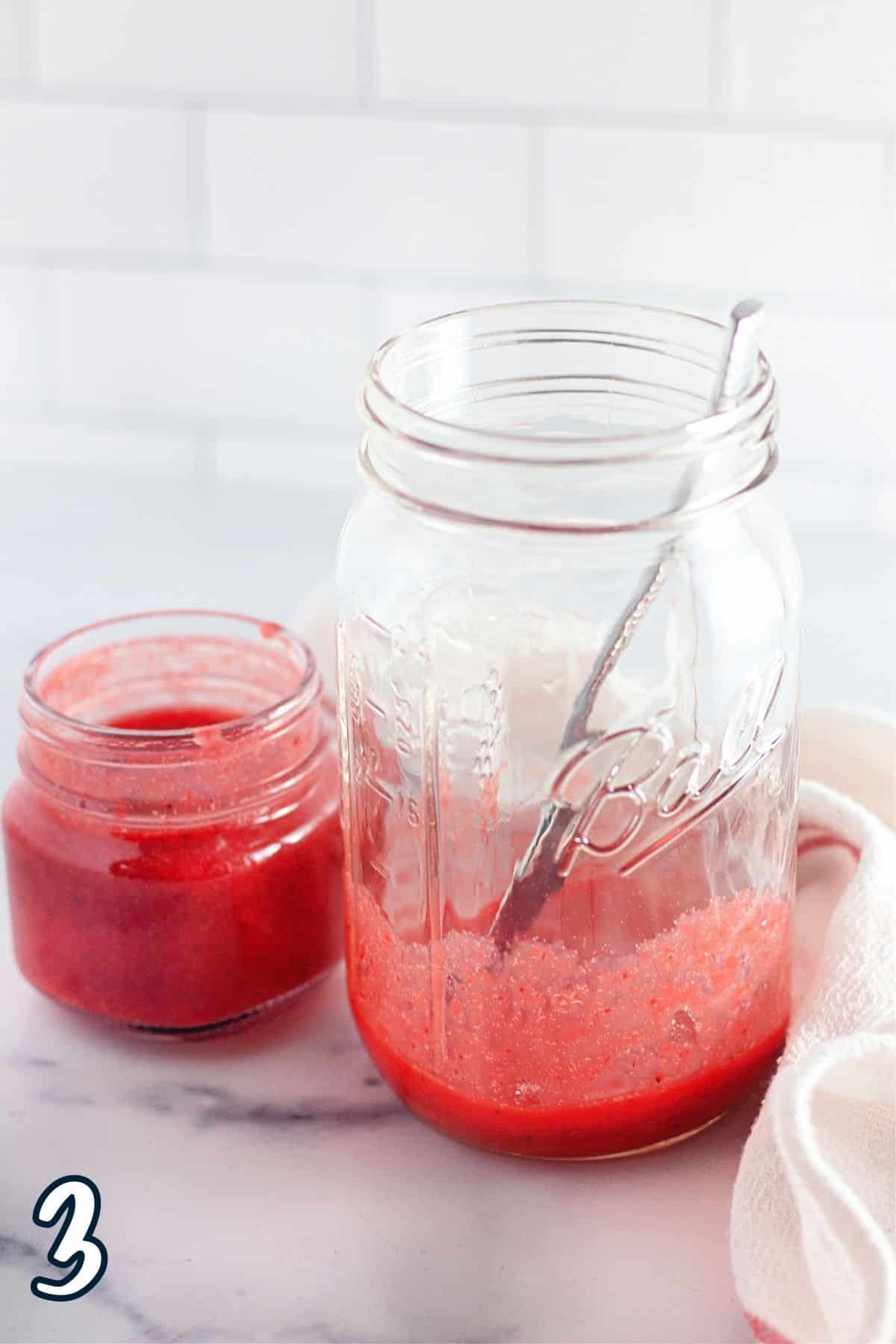 Lemonade mix and strawberry puree mixed together in a glass. 