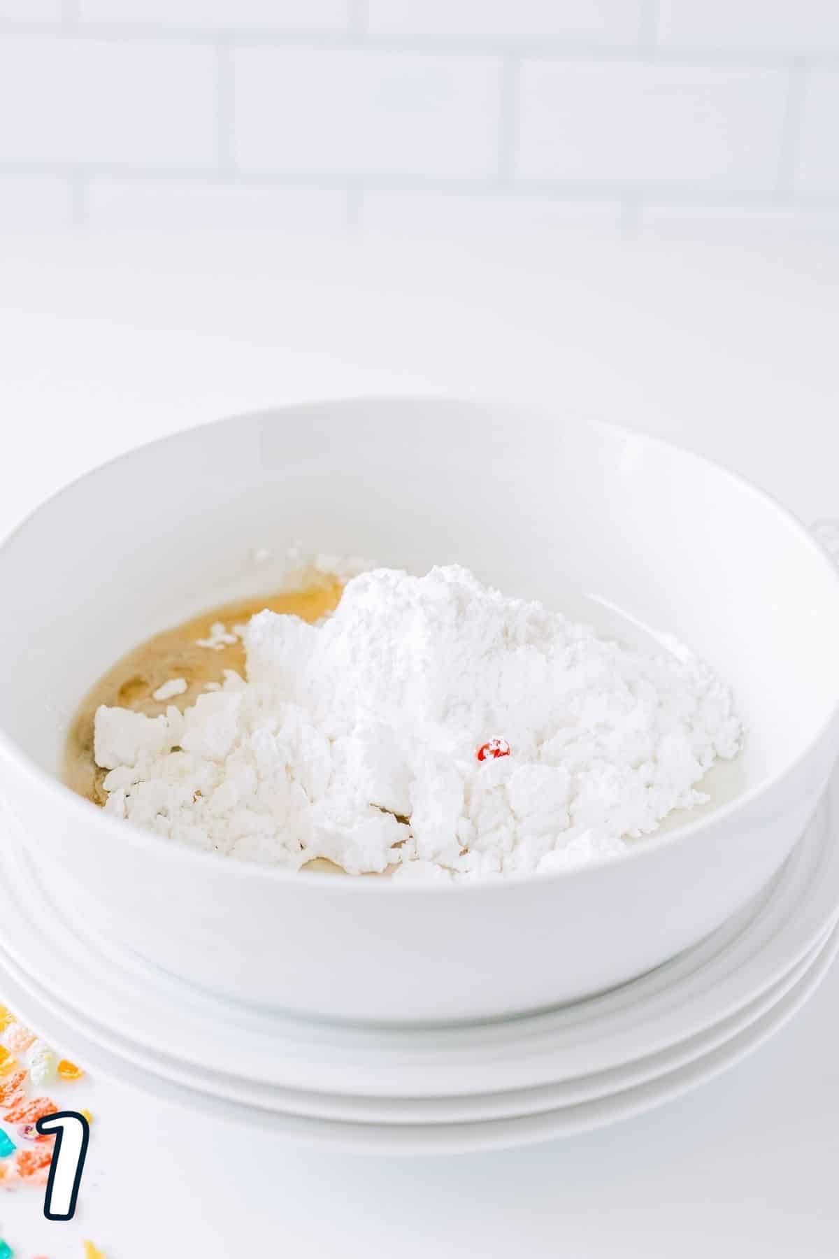 Powdered sugar, milk, vanilla and strawberry extract in a white mixing bowl.