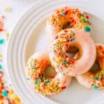 4 Fruity Pebble Cereal Donuts on a white plate.