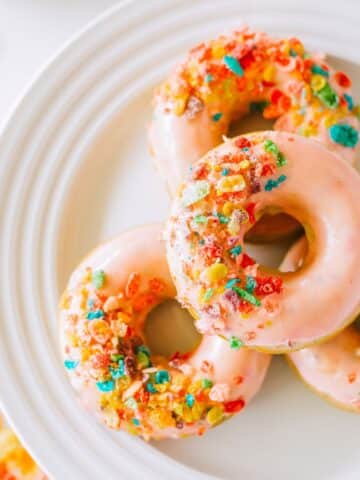 4 Fruity Pebble Cereal Donuts on a white plate.