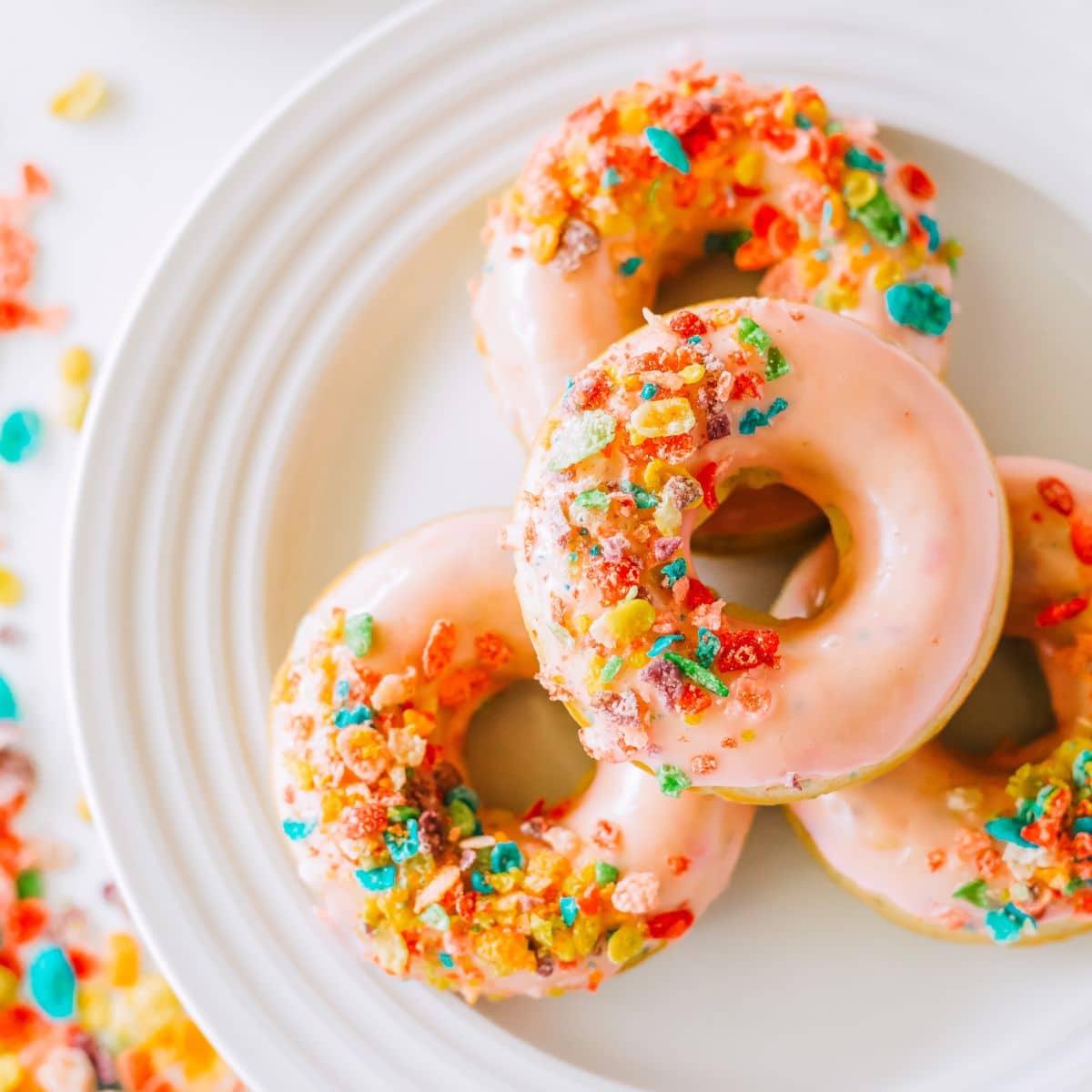 4 Fruity Pebble Cereal Donuts on a white plate.