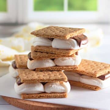 A stack of smores on parchment paper in front of a window.